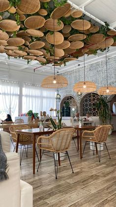 a room filled with lots of wicker furniture and plants hanging from the ceiling above