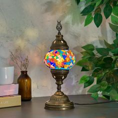 a colorful lamp sitting on top of a table next to a cup and planter