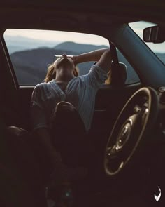 a woman sitting in the passenger seat of a car with her head resting on her hand