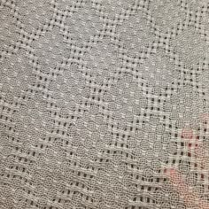 a person's hand is seen through the lace on a bed sheet that has been crocheted