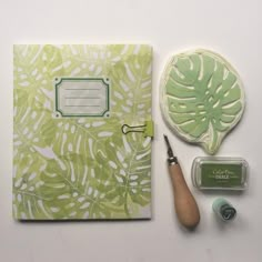 the contents of a green and white palm leaf notebook, scissors, stamp pad, and waxing supplies