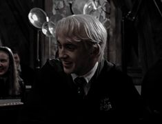 a young man with blonde hair wearing a harry potter outfit and looking to his left