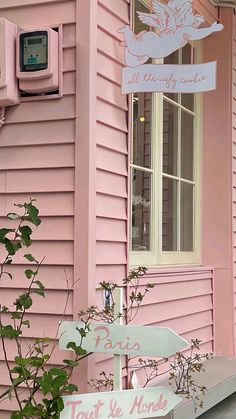 a pink house with a sign and potted plant