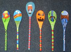 six spoons with different designs on them are lined up in a row against a gray background