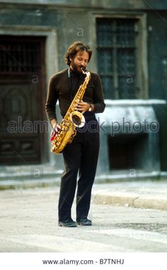 a man standing on the street playing a saxophone