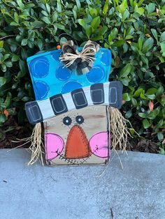 a painted box sitting on top of a cement slab next to some bushes and trees