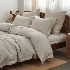 a bed with white linens and pillows in a room next to a lamp on a table