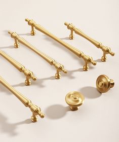 six golden handles and knobs on a white surface