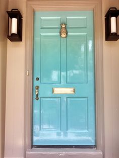 a blue front door with two black lanterns on the side and one white light above it