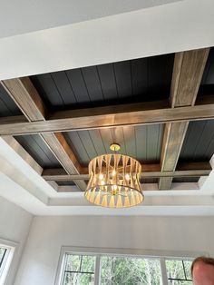 a man standing in front of a window under a light fixture with wood beams on the ceiling