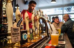 a man standing behind a bar filled with lots of beer