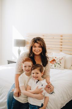 a woman and two children sitting on a bed