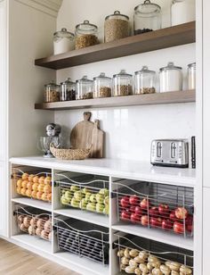 a kitchen with open shelves filled with fruits and veggies on top of it