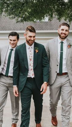 three men in suits and ties standing next to each other with one man wearing a green tie