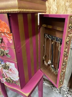 a pink and gold dresser with jewelry in it