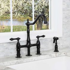 a black faucet sitting on top of a white counter next to a window