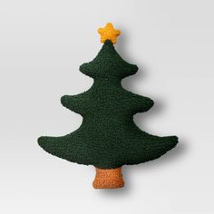 a knitted christmas tree ornament hanging on a wall with a star on top