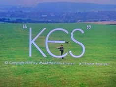 a man standing on top of a lush green field next to a large sign that says kes