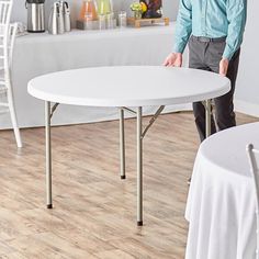 a man standing next to a white table