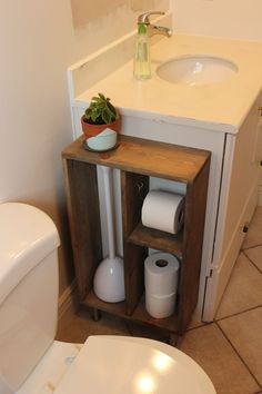 a white toilet sitting next to a wooden cabinet in a bathroom under a sink and mirror