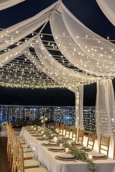 the tables are set up with white linens and lights strung over them for an elegant wedding reception