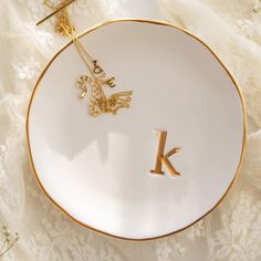 a white and gold plate with the letter k on it