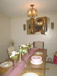 the table is set for a birthday party with pink and white flowers in vases