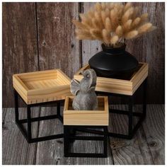 an elephant figurine sitting on top of two small wooden trays and a vase