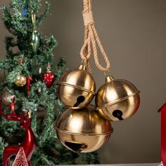 two bells hanging from a rope in front of a christmas tree with ornaments around it