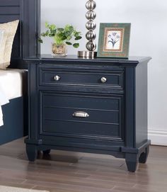 a night stand with two drawers and a lamp on it's end table next to a bed