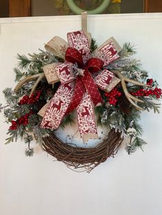 a christmas wreath with deer antlers and red berries hanging on a door hanger