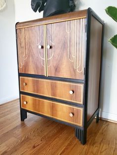 a wooden cabinet with two drawers on top of it next to a potted plant