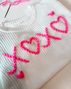 a knitted sweater with the word love spelled out in pink crochet on it