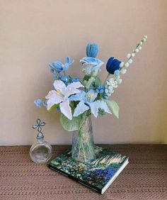 a vase filled with blue and white flowers on top of a table next to a book