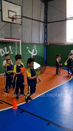 several children are playing basketball on an indoor court with orange cones in the foreground