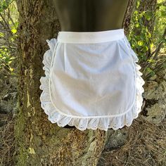 a mannequin is standing next to a tree wearing a white ruffled skirt