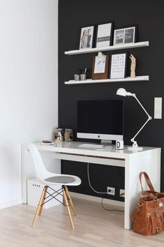 a white desk with a computer on top of it next to a brown bag and some pictures