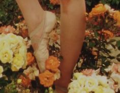 there is a woman's feet in the middle of flowers with her shoes on