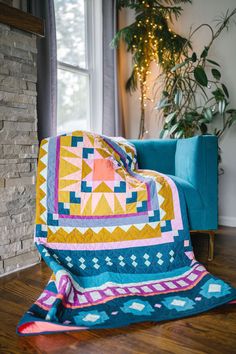 a couch with a blanket on top of it in front of a window next to a potted plant