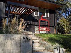 a red chair sitting on the side of a building next to a cement wall and steps