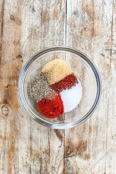 three different spices in a glass bowl on a wooden table