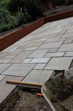 a brick patio being built with tools laying on the ground