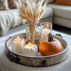 a tray with candles and pumpkins in it on a table next to a couch