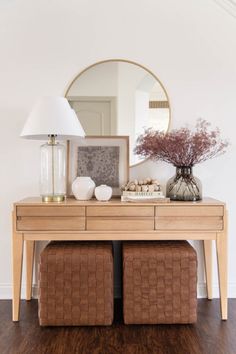 a wooden table with two baskets underneath it and a mirror on the wall behind it