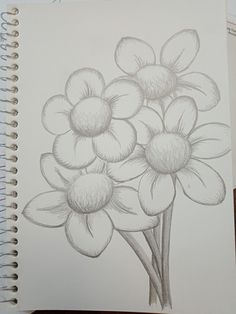 a drawing of some flowers on top of a book with pencils in front of it