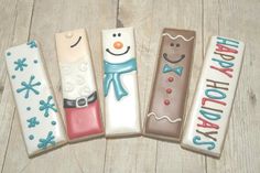 four decorated holiday candles sitting on top of a wooden table