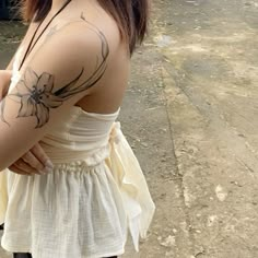 a woman with a flower tattoo on her arm and shoulder is standing in the street