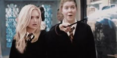 two young people dressed in harry potter costumes, one holding a wand and the other pointing at something