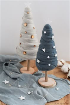 two small christmas trees sitting on top of a wooden table