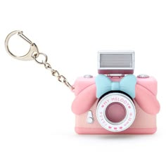 a pink camera keychain with a blue bow on the front and white background